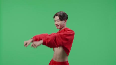 the smiling asian transgender male dancing sides while standing on green screen studio