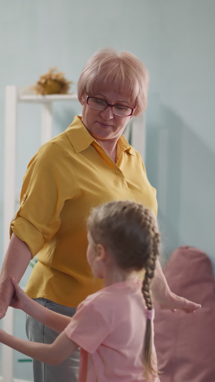 little girl teaches an elderly lady to dance, her granddaughter spends fun time with her grandmother and exercises