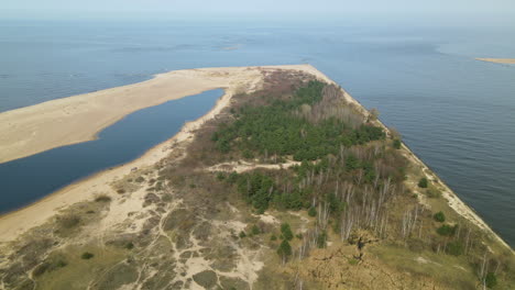 beautiful aerial footage of vistula river entering baltic sea at mewia lacha nature reserve during a sunny day, aerial side flight shot