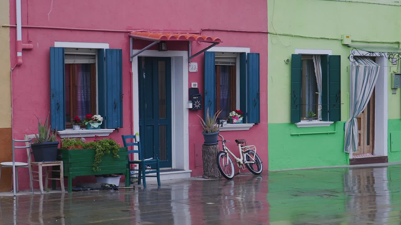 Ladies Bicycle leans against Colourful painted cottage on rainy day
