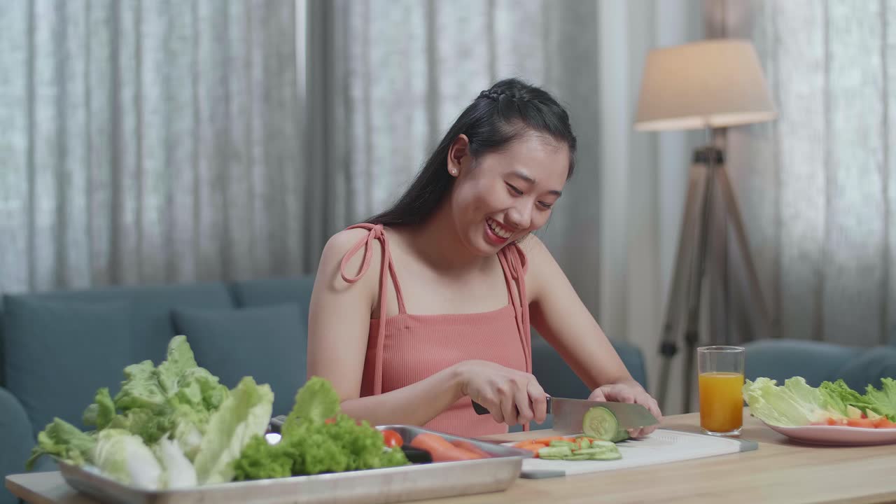 미소 짓는 아시아 여성 이 집 에서 건강 한 음식 을 준비 하는 동안 호박 을 잘라