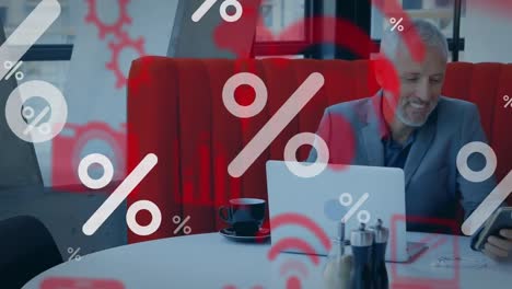 porcentaje e iconos digitales contra un hombre de negocios caucásico que usa un teléfono inteligente en la oficina