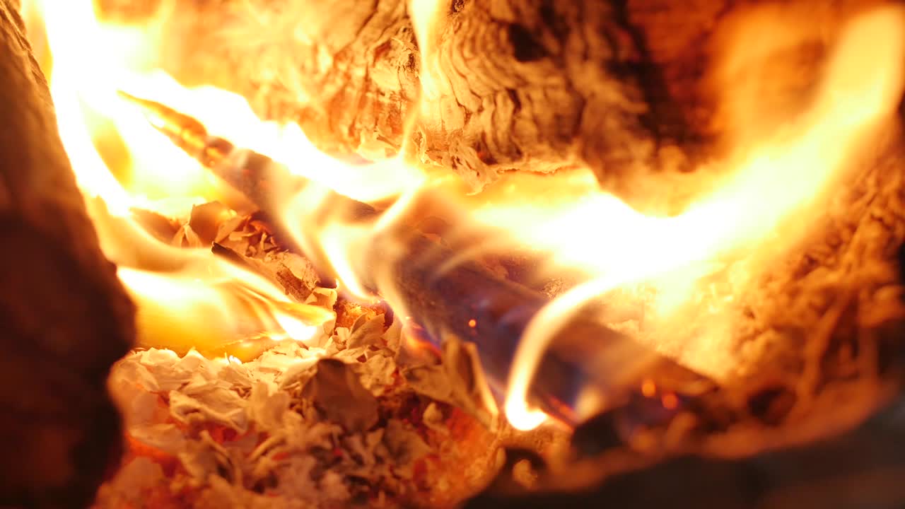 el árbol se quema hermosamente en la chimenea. la mano masculina pone leña en la estufa. quemando fuego en la chiminea. 4k. abrazadera de bucle de chimenea de llama media