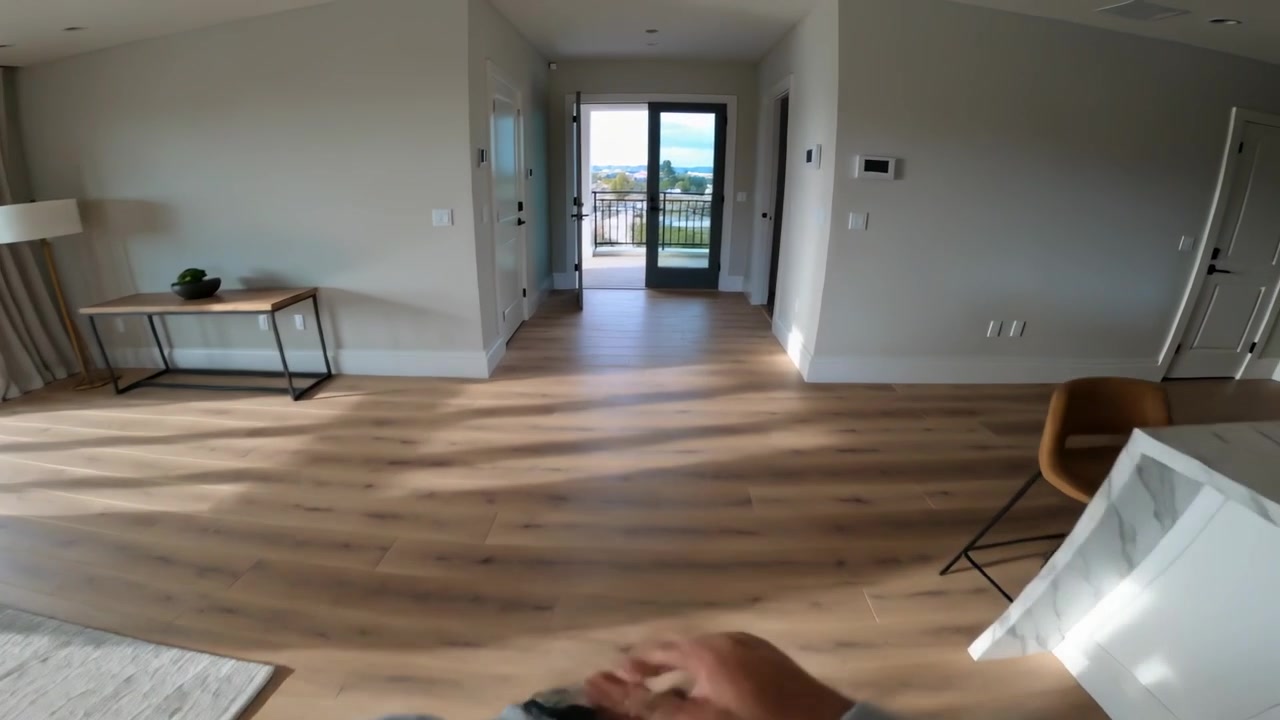 Tapping smartwatch person wearing light top walking through open living room past island to balcony