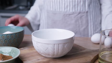 Female-Chef-In-Stripe-Apron-Cracking-Fresh-Eggs-Into-A-Bowl-At-The-Kitchen