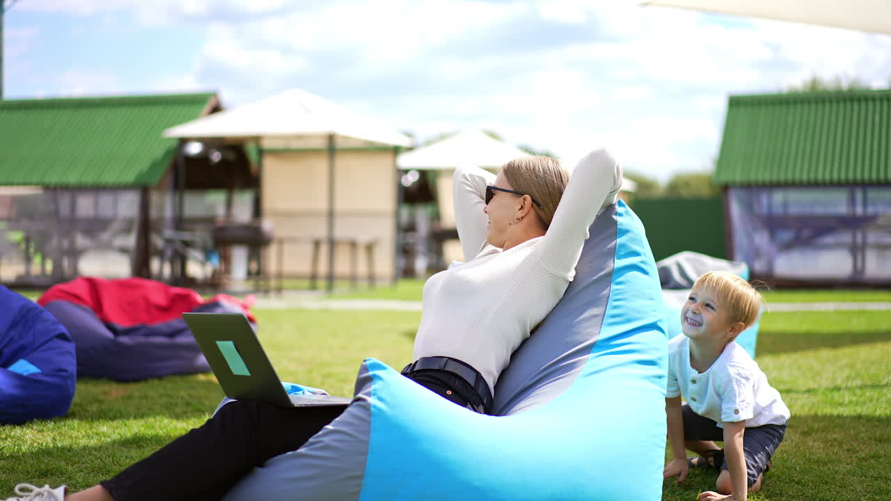 Woman working from a park with her child