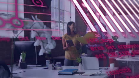 two coworkers sharing documents and discussing in business office, with pink projected graphs