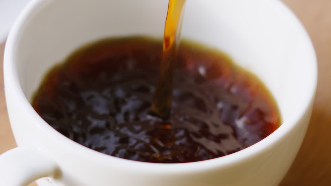 Fresh Morning Coffee Being Poured into White China Mug in Slow Motion with Bubbles on Top After Pouring is Finished