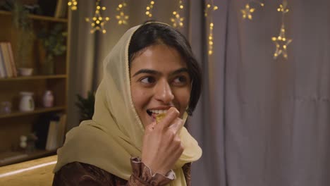 familia musulmana sentada alrededor de una mesa en casa comiendo para celebrar el eid 3