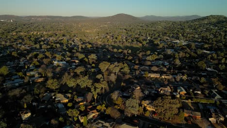 drone glides sideways over hilly rivett suburb, showcasing rooftops stretching endlessly into the golden horizon