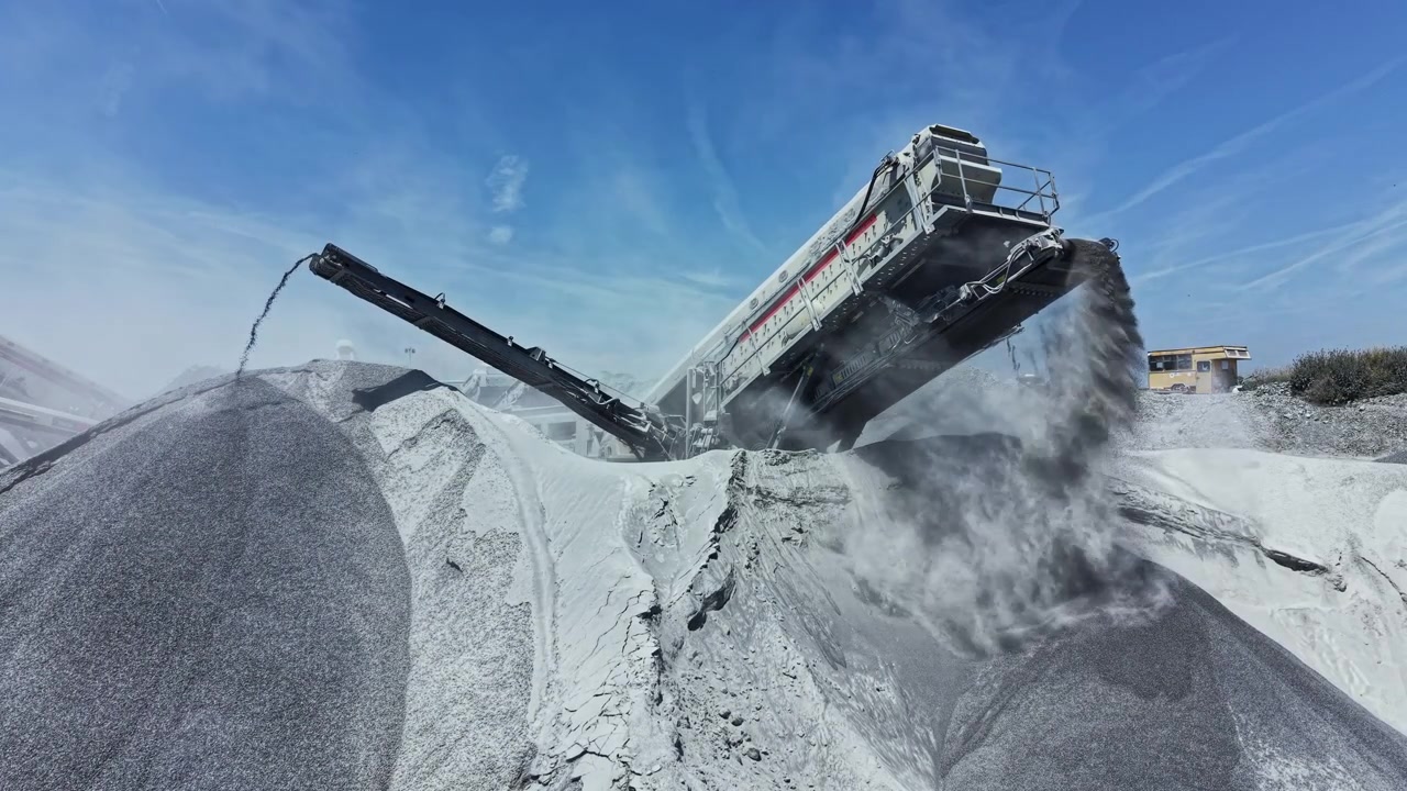 Granite quarry operation with machinery processing stones and transporting material under a clear sky
