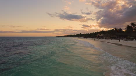 Vista-Aérea-Cerca-Del-Océano-Caribe-En-La-Playa-Akiin-En-Tulum,-México-Durante-La-Puesta-De-Sol-Con-Gente-Disfrutando-De-Sus-Vacaciones-En-La-Playa