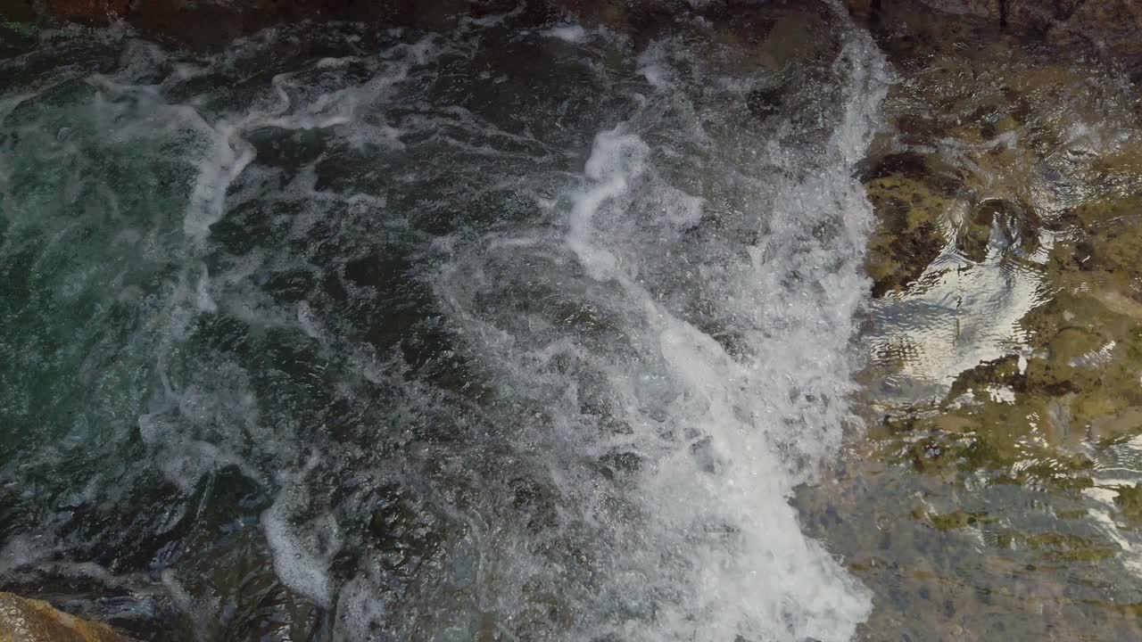L'acqua di mare si riversa dentro e fuori da uno stretto canale roccioso con la marea, primo piano