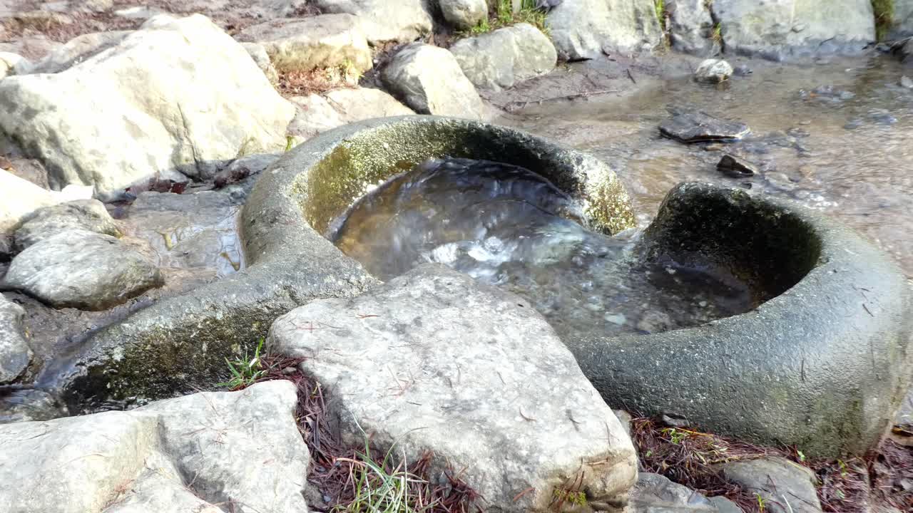 Fiume che scorre attraverso un bacino roccioso liscio, eroso e levigato dagli agenti atmosferici, in primo piano.