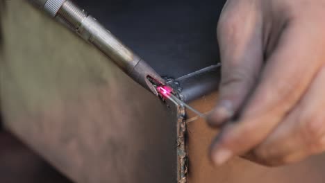 máquina de soldadura láser con pistola de mano. la soldadura láser se muestra en primer plano.