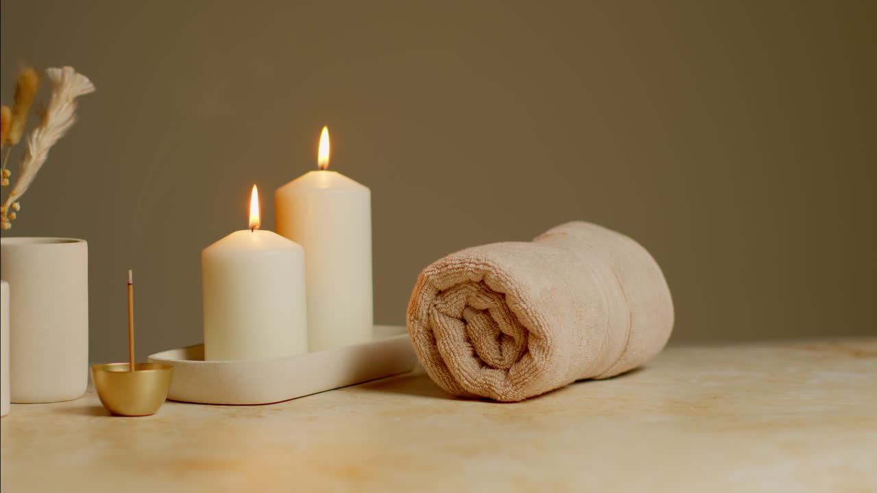 vida muerta de velas encendidas con hierbas secas, incienso y toallas suaves como parte de la relajante decoración del día de spa