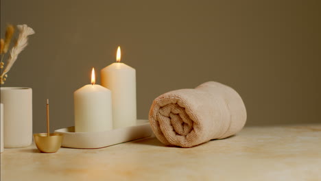 still life of lit candles with dried grasses incense stick and soft towels as part of relaxing spa day decor