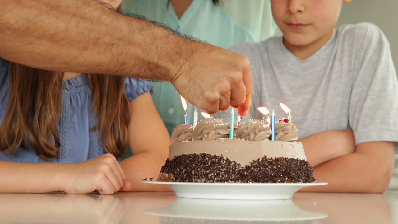 padre encendiendo velas en el pastel de cumpleaños para su familia