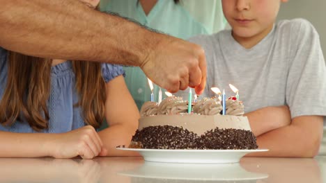 Father-lighting-candles-on-birthday-cake-for-his-family