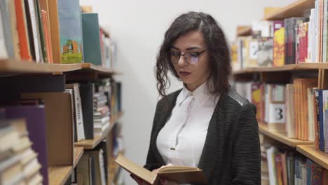 beautiful librarian reads a book in the stacks of a library