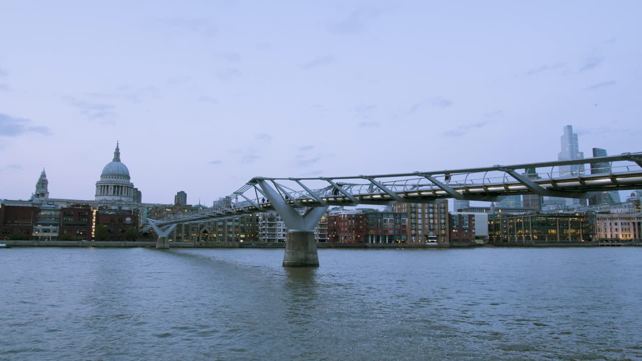 noche del puente del milenio con san pablo al fondo y gente caminando