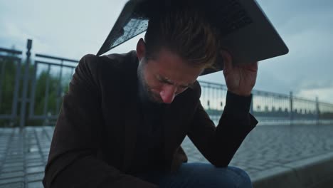 man with laptop in the rain