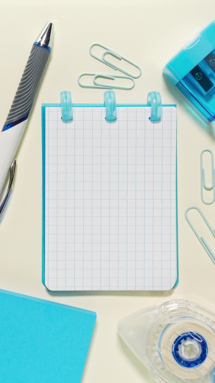 Portrait stop-motion loop of blue stationery framing a grid notepad used as the central copy space