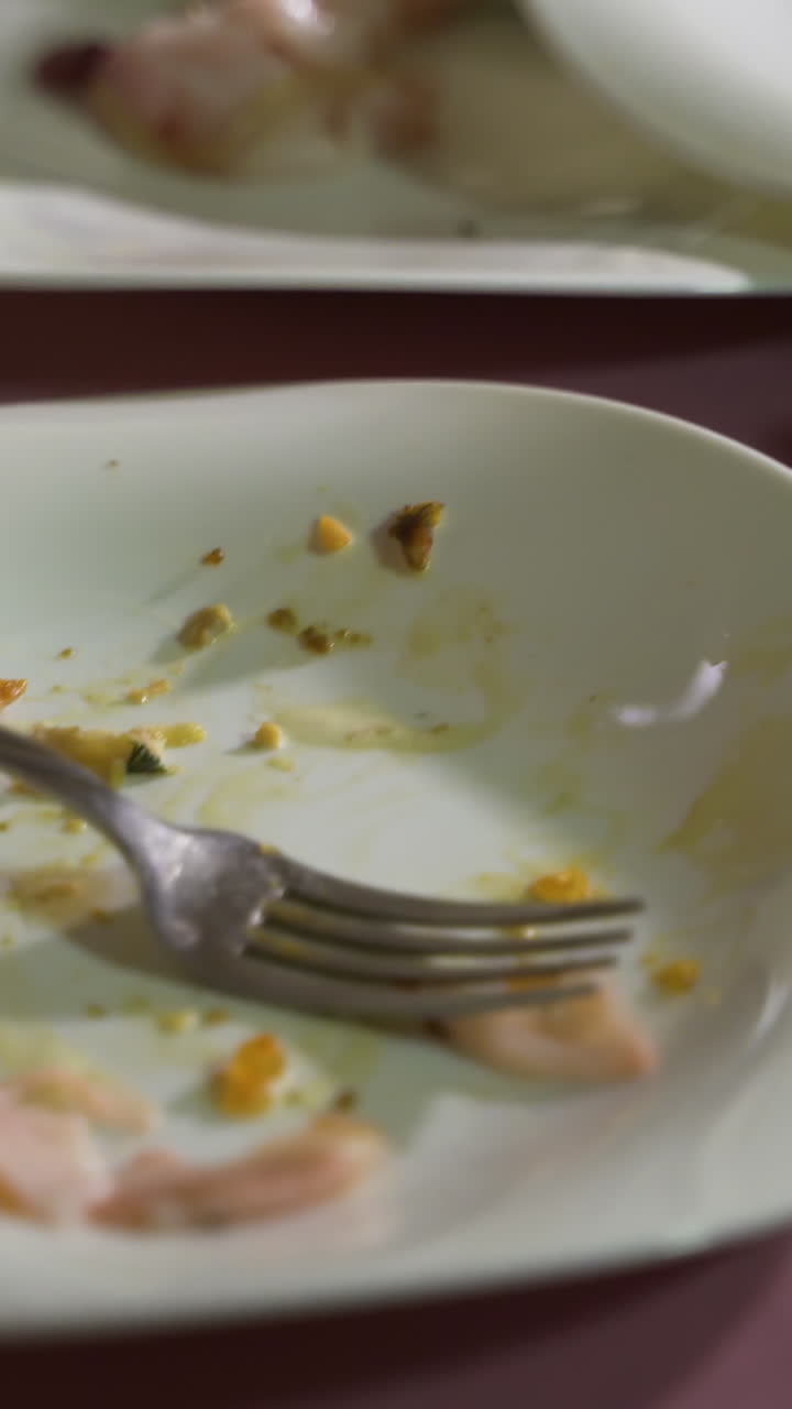 crumbs of dishes are on white plates on a pink background in the restaurant after the holiday. Leftovers Vertical video