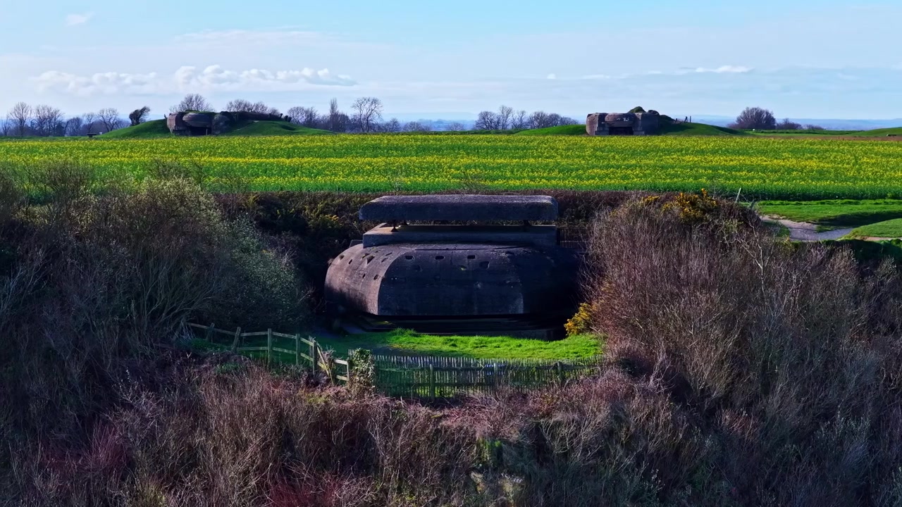 La batteria di Longues-sur-Mer si erge tra campi verdi lussureggianti e sotto un cielo azzurro limpido. Ideale per documentari storici o contenuti educativi.