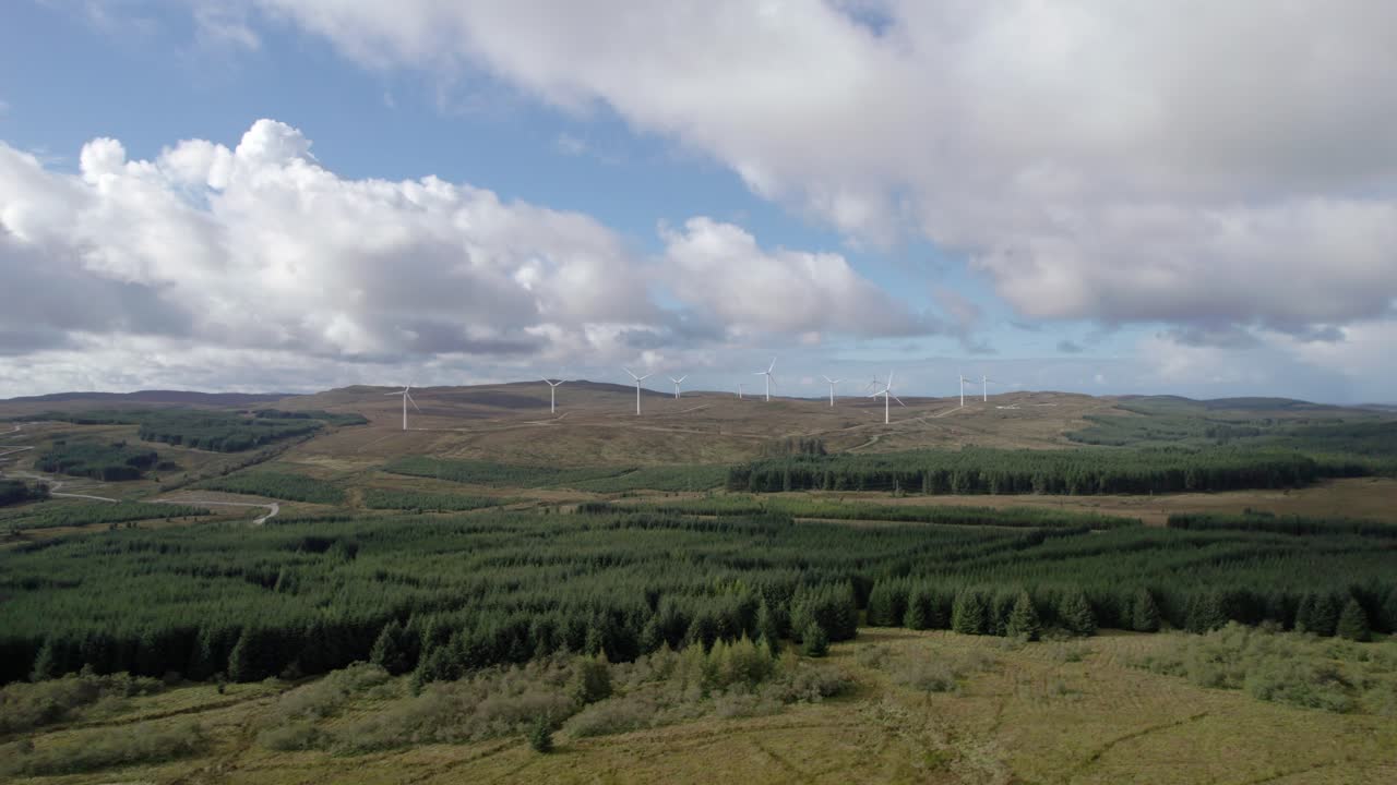 imágenes aéreas de drones volando hacia turbinas eólicas en un parque eólico escocés rodeado de plantaciones forestales de coníferas comerciales en la península de kintyre, argyll, escocia