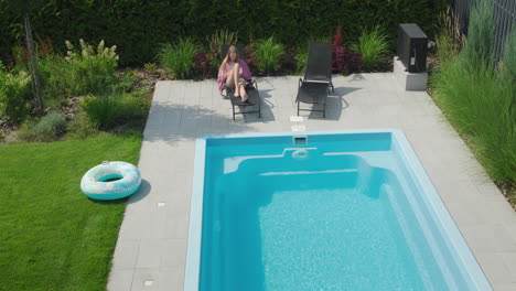 Teenage-girl-relaxing-by-the-pool,-lying-in-a-sun-lounger