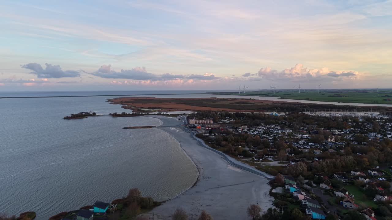 Aerial flyover coastline with ebbtide mud at sandy beach in American town. Sunset time in Autumn season. Wide shot. Houses and homes on island of USA
