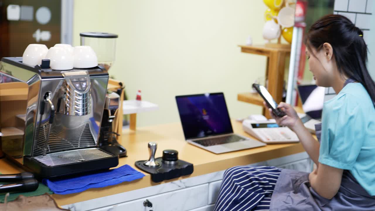 레스토랑 매니저가 커피에서 웹을 서핑하고 스마트폰으로 대화하고 있습니다.