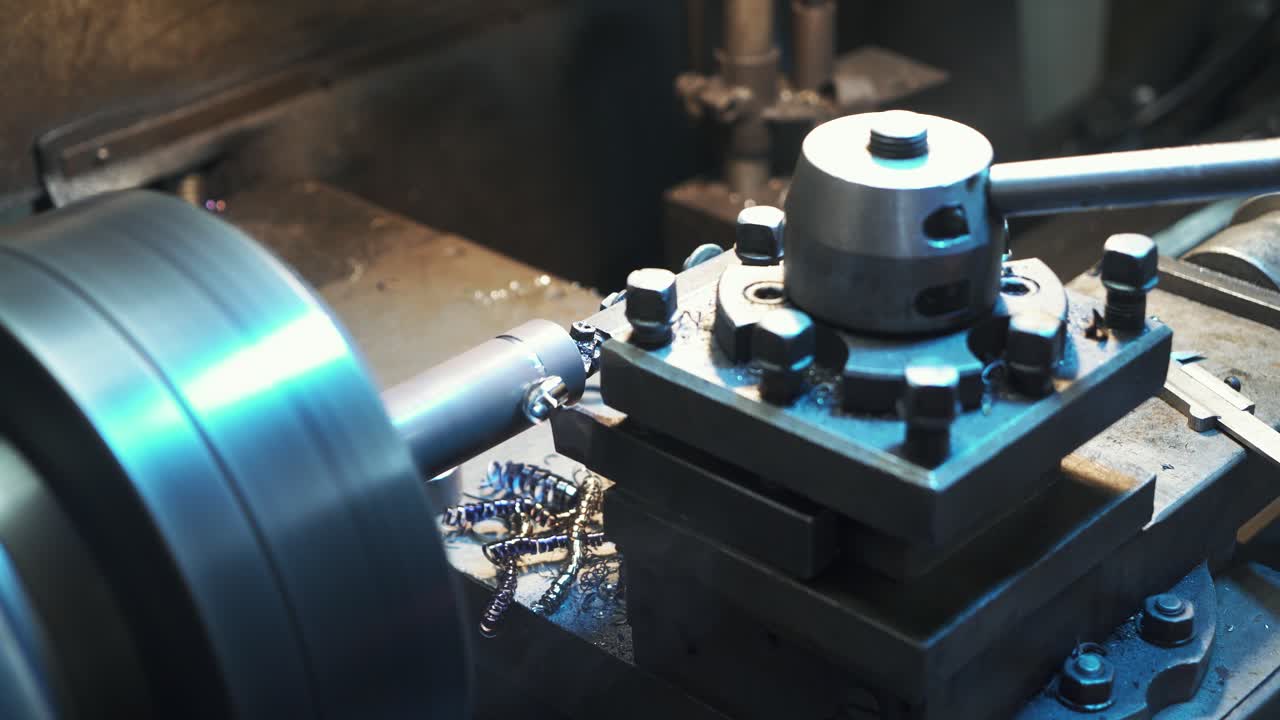 Metalworking industry: cutting steel metal shaft processing on lathe machine in workshop. Selective focus on tool