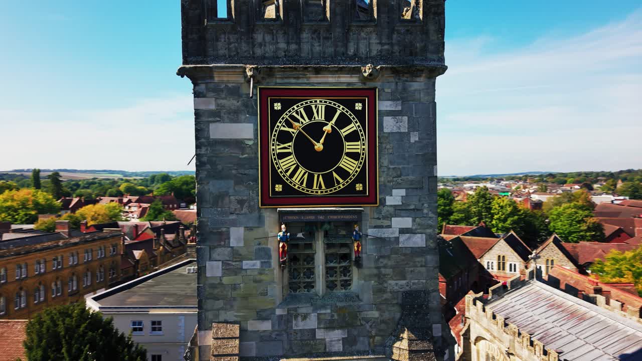 Close aerial drone shot of the historic clock tower of St Thomas's Church in Salisbury Wiltshire England with town rooftops and countryside in the background