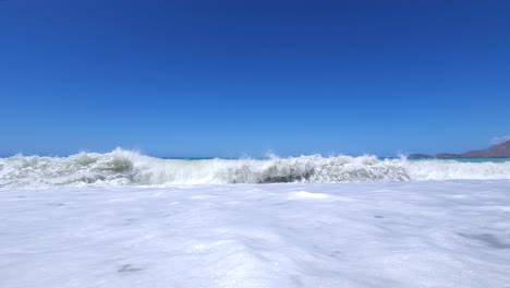 white waves splashing on beach, beautiful sea background with blue sky in mediterranean shoreline