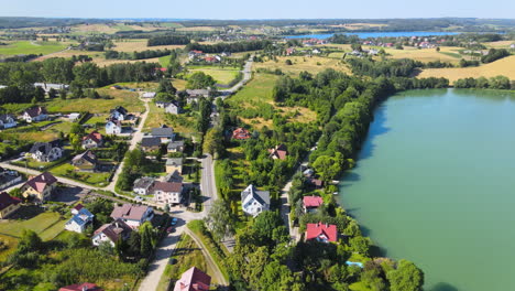 Vista-Aérea-De-La-Zona-De-Viviendas-Rurales-De-Lujo-Junto-Al-Hermoso-Lago-En-El-Campo-Durante-Los-Rayos-Del-Sol