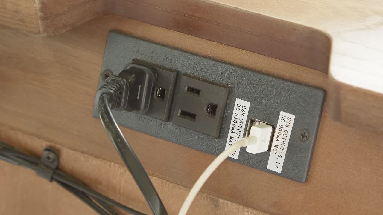 Camera zooms on table outlet with two-prong plugs and USB lead