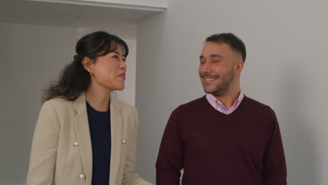 maestros masculinos y femeninos hablando mientras caminan a lo largo del pasillo en el edificio de la escuela juntos 1