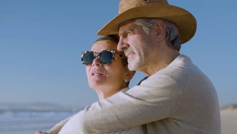 una pareja romántica de ancianos abrazándose mientras hablan y disfrutan de la vista en la playa