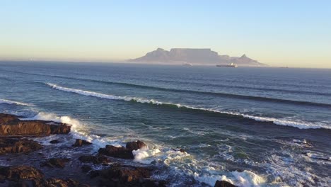 Luftaufnahme-Des-Sonnenuntergangs-Am-Strand-Von-Kapstadt-Mit-Dem-Tafelberg-Im-Hintergrund