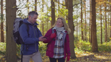 Älteres-Paar-Läuft-Durch-Die-Herbst--Oder-Winterlandschaft-Und-Schaut-Auf-Die-Navigations-App-Auf-Dem-Mobiltelefon,-Um-Den-Weg-Zu-Finden-–-Aufgenommen-In-Zeitlupe