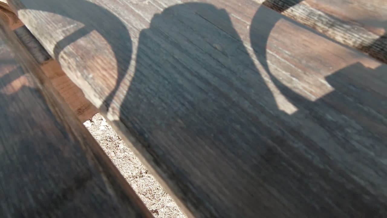 Onboard drone footage captures landing approach on wooden table, showing propeller motion and shadow dynamics from drone's perspective. Ideal for drone technology showcases,