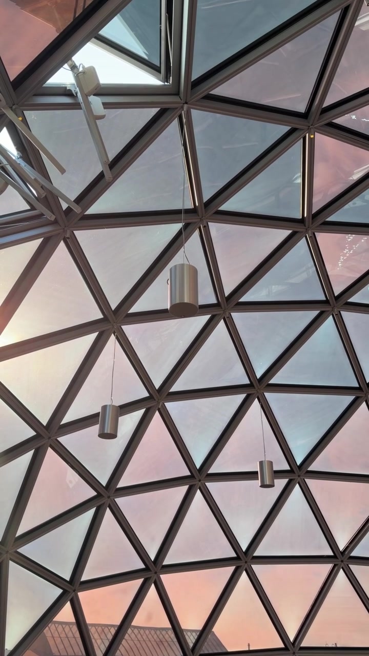 Interior view of modern geodesic dome roof with lounge seating at sunset