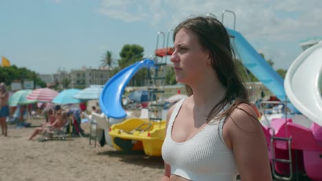 mujer joven rubia en la playa de arena mirando el mar mediterráneo