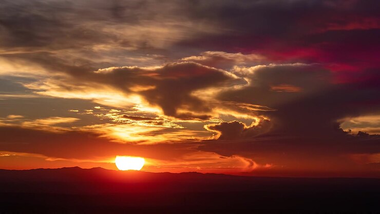 Tramonto drammatico con nuvole luminose su una catena montuosa scura