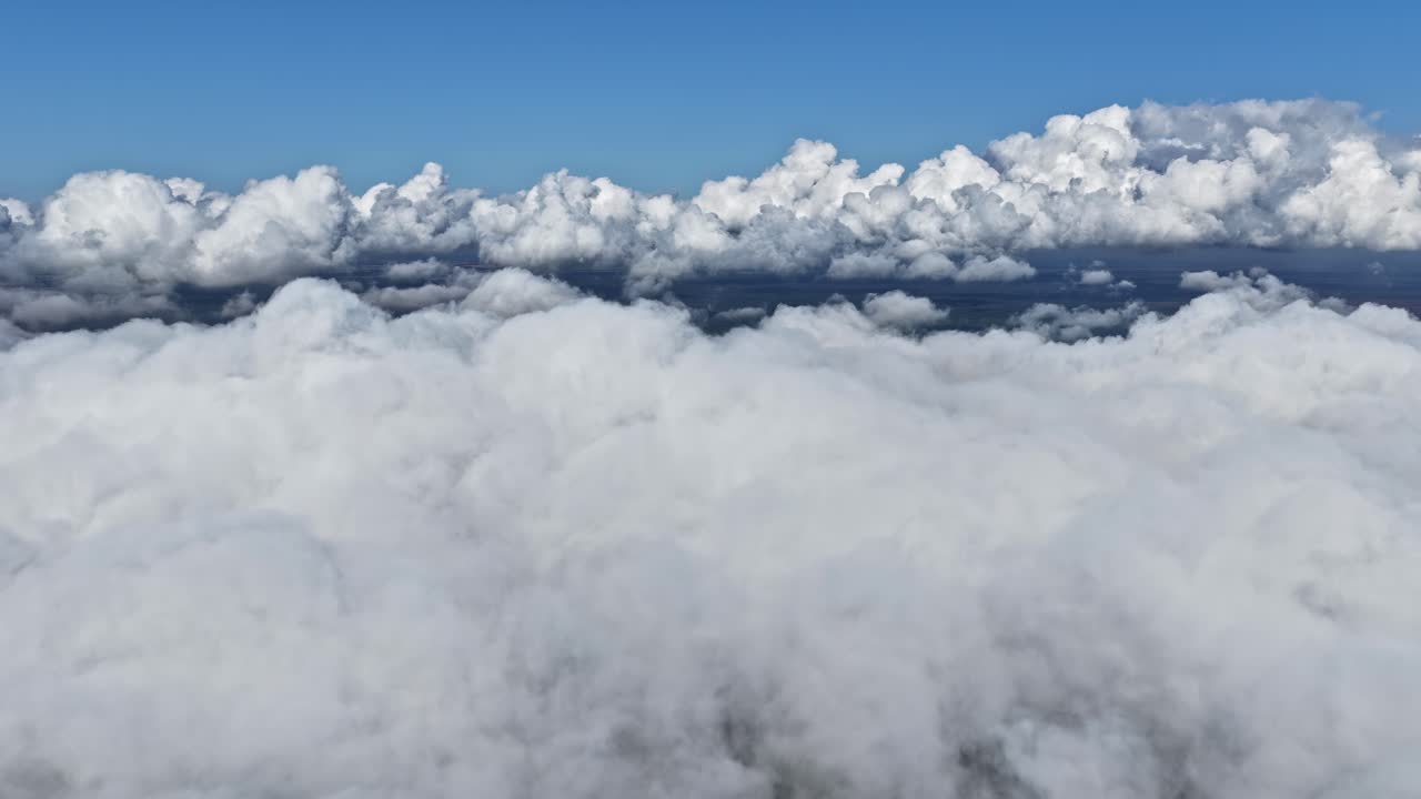 Soft white clouds stretching across a deep blue sky, captured from above in a peaceful aerial view