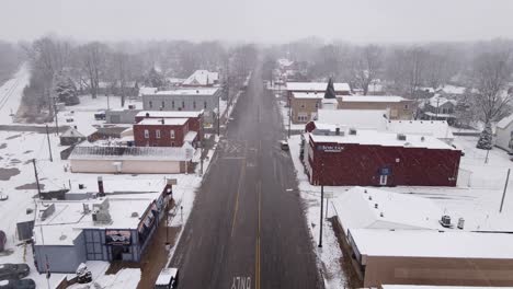 Town-center-of-Carlton-in-Michigan-during-snowfall,-aerial-drone-view