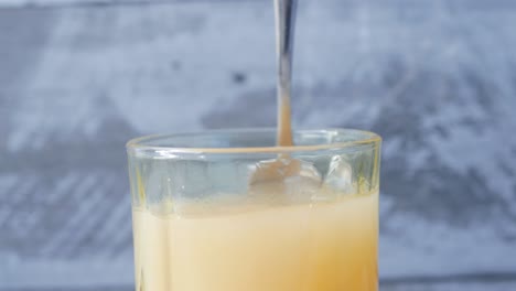 Mixing-white-sugar-in-a-glass-of-juice-,