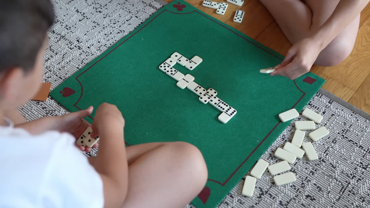 Crianças jogando dominó em uma mesa verde